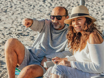 Older man and woman on beach. Man is pointing to something in the distance.