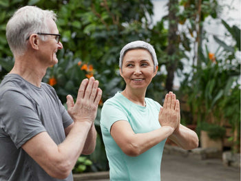 Woman and man looking at each other while doing yoga in garden.